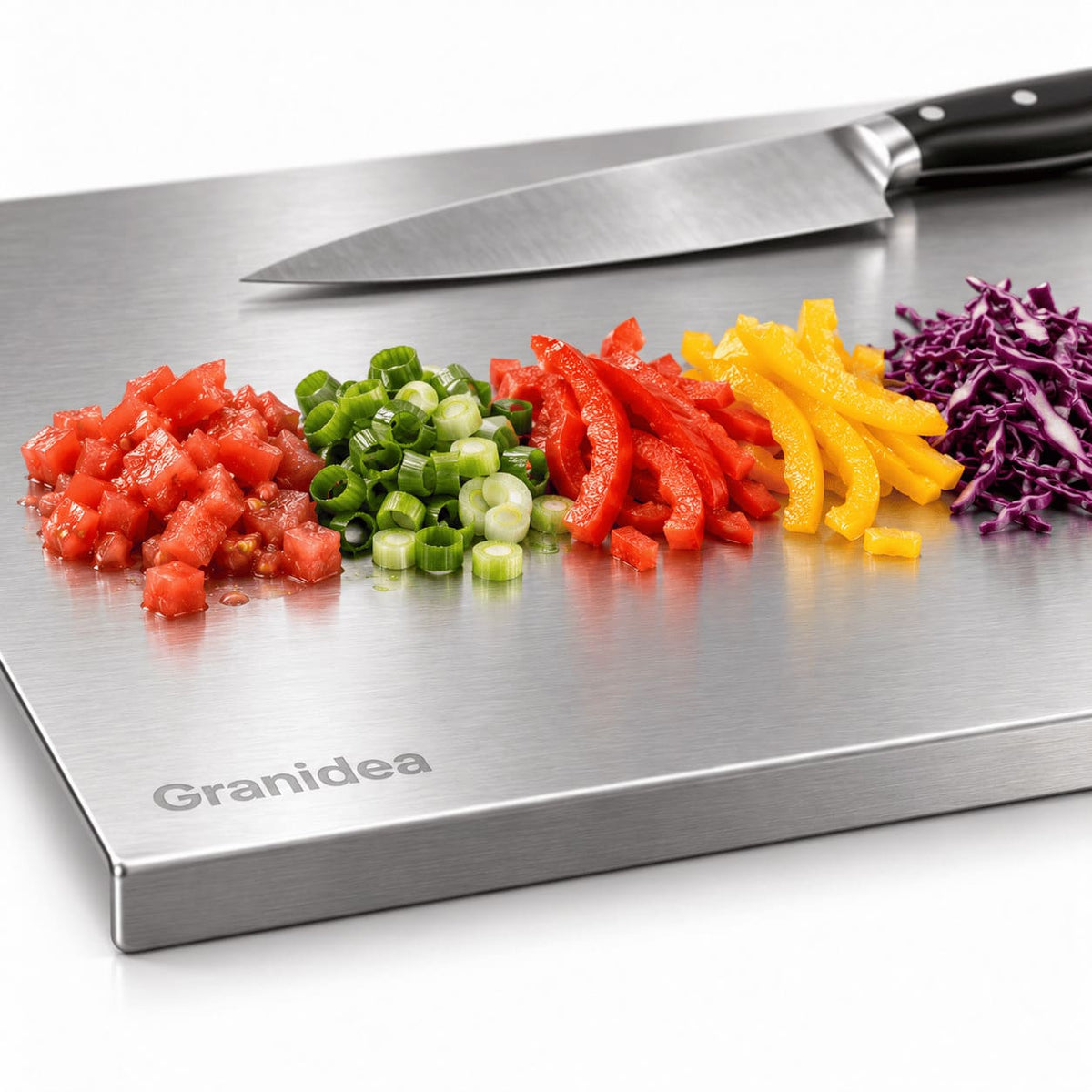 Primer plano de un cuchillo sobre la tabla de acero inoxidable con verduras picadas